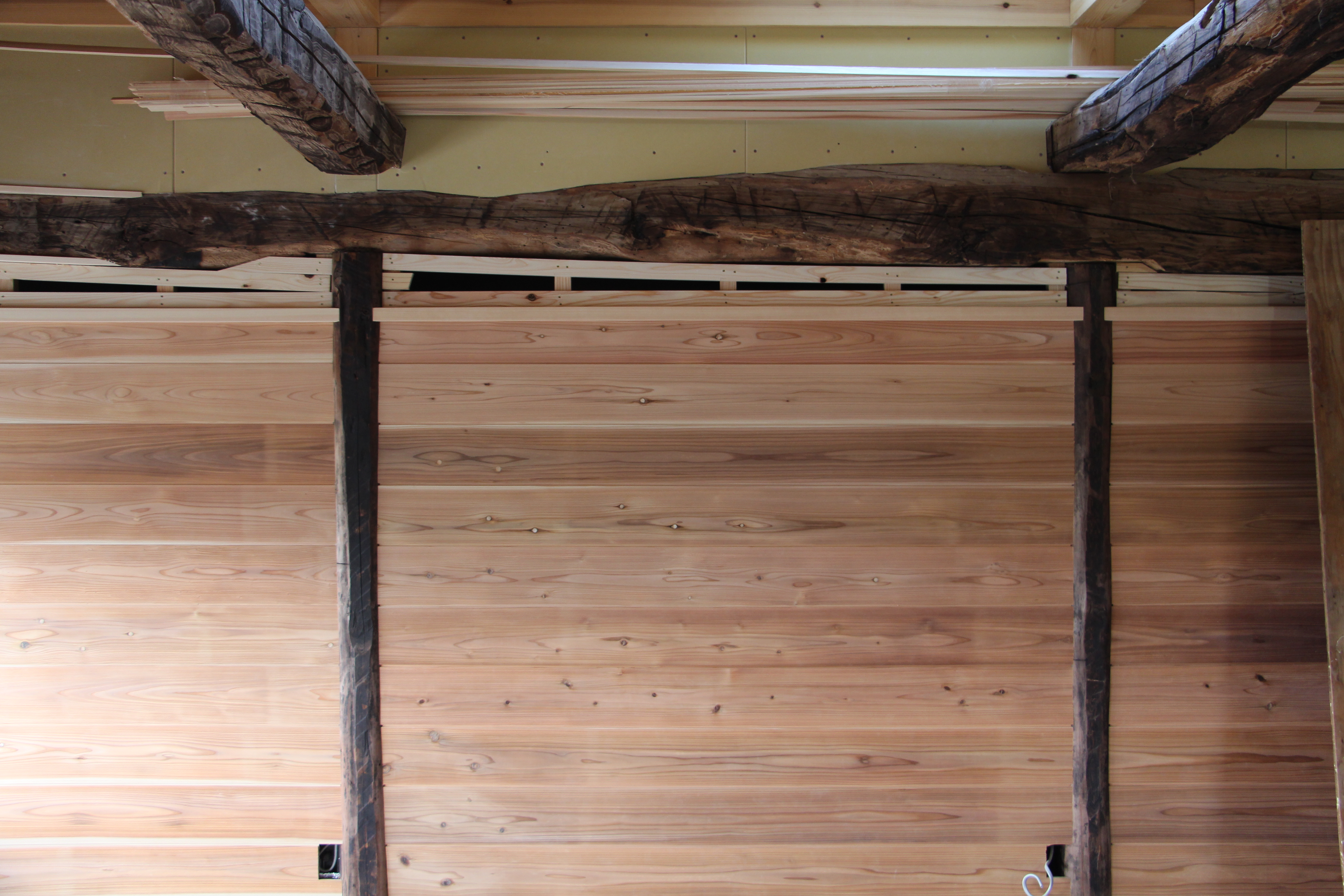 小屋裏部屋の壁面です。古材丸太柱のちょうな斫の面に杉板を合わせて張りました。手間のかかる丁寧な仕事です。