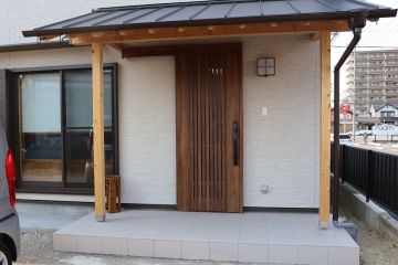 玄関の戸は木製ではなく、アルミサッシの片引き戸です。ポーチは深い木製の軒です。